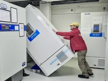 A person transports a new ULT freezer on a cart into the freezer room.