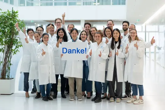 Forschungsgruppe des DKFZ hält Schild mit "Danke" nach oben.