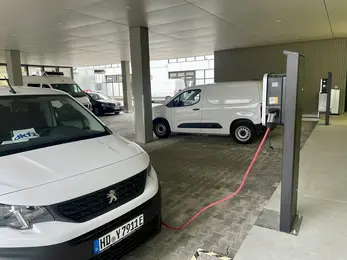 A DKFZ transport van charges at an electric charging station outside the main building.