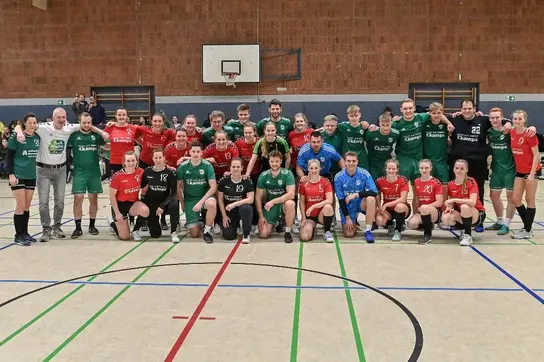 Eine große Gruppe von jungen Handballspielern und -spielerinnen posiert gemeinsam in einer Sporthalle.