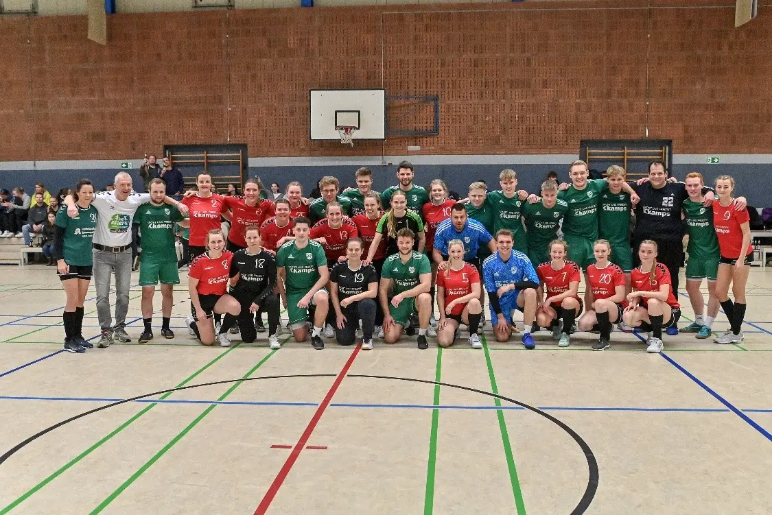 Eine große Gruppe von jungen Handballspielern und -spielerinnen posiert gemeinsam in einer Sporthalle.