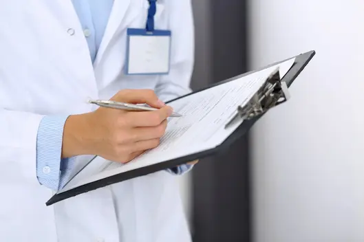 Medical person writes something on a clipboard. 