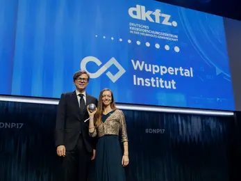 The DKFZ sustainability coordinator receives the award on stage from Ralph Caspers.