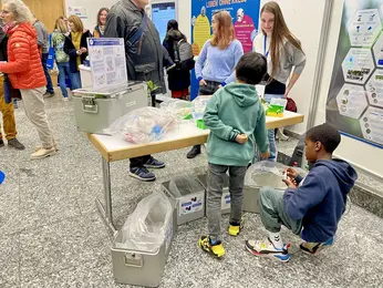 Two children kneel on the floor, sorting plastic into the appropriate metal autoclave containers.