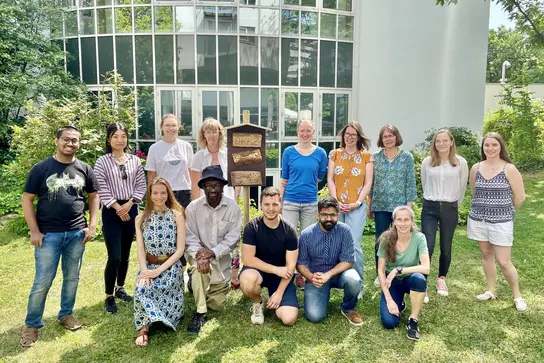 Sustainability Group poses in green outdoor space around insect nesting aid