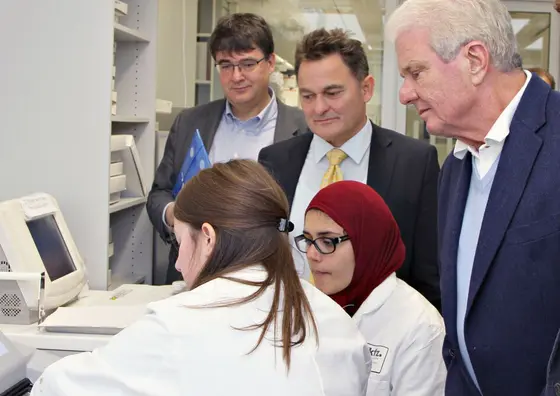 Dietmar Hopp (rechts) lässt sich von HI-STEM-Wissenschaftlerinnen die neuesten Ergebnisse zeigen. Außerdem dabei: Der DKFZ-Vorstandsvorsitzende Michael Baumann (links) sowie HI-STEM-Direktor Andreas Trumpp (Mitte).