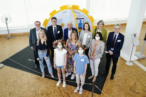 Gruppenbild vor der HPV-Mitmach-Station: Hintere Reihe: Dr. Thomas Fischbach, Präsident vom Berufsverband der Kinder- und Jugendärzte (BVKJ), Prof. Michael Baumann, Vorstandsvorsitzender DKFZ, Gerd Nettekoven, Vorstandsvorsitzender der Deutschen Krebshilfe, Dr. Ulrike Helbig, Lt. Berliner Büro der Deutschen Krebshilfe, Dr. Heike Kramer, Vorstandsvorsitzende der Ärztlichen Gesellschaft für Gesundheitsförderung (ÄGGF). Prof. Dr. Thomas Seufferlein, Präsident der Deutschen Krebsgesellschaft. Vordere Reihe: Susanne Klehn, Fernsehmoderatorin, Felicitas Then, Bloggerin und Fernsehköchin, Prof. Sigrun Smola, Universitätsklinikum des Saarlandes. Ganz vorn: Mara und Veit.