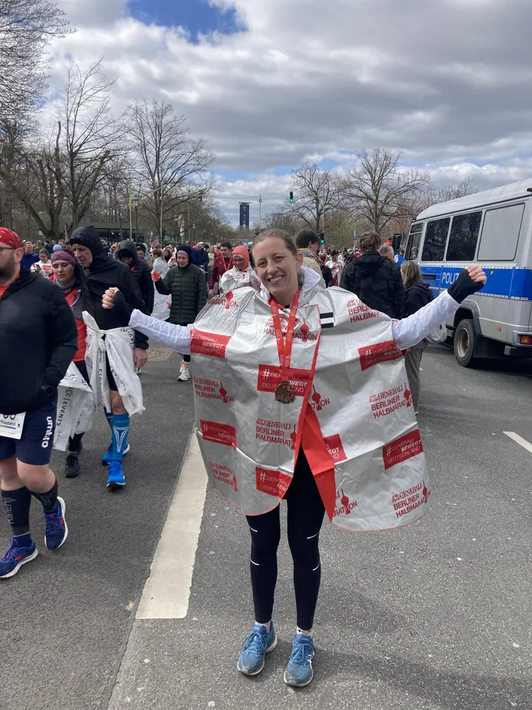 Sophie Laas steht mit einer Medaille um den Hals im Zielbereich des Berlin Marathons.