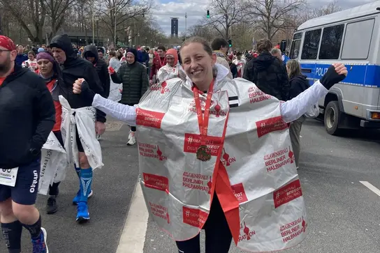 Sophie Laas steht mit einer Medaille um den Hals im Zielbereich des Berlin Marathons.