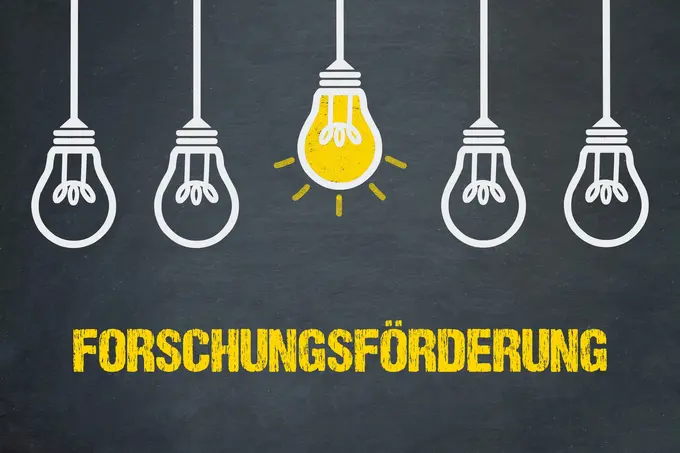 Forschungsförderung / Tafel mit Glühbirnen Bildbeschreibung: Fünf Glühbirnen sind angeordnet, von denen eine in leuchtendem Gelb hervorsticht. Darunter steht in großen, gelben Buchstaben das Wort „FORSCHUNGSFÖRDERUNG“. Das Bild symbolisiert innovative Ideen und Unterstützung für Forschungsprojekte.